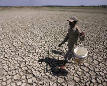 A villager looks for water as he walks in a dried out lake.