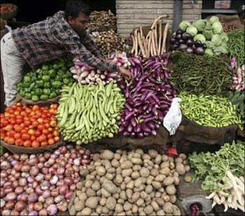 A vendor arranges vegetables at a market.