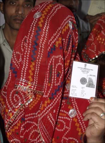 A woman shows her voter identity card as she waits for her turn to cast her ballot at a polling station in Bikaner.