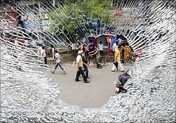 People seen through the broken windshield of a vehicle damaged by a mob during a strike in Siliguri.