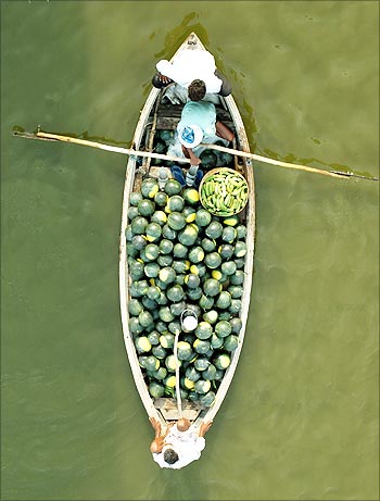 Indian farmers carry watermelons on a boat across the Ganga in Allahabad.