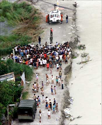 Residents of Minalin town north of Manila waiting as a rescue helicopter delivers relief goods.