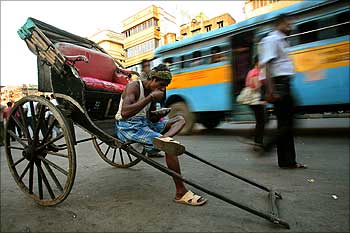 A rickshaw puller eats beside a busy road in Kolkata.