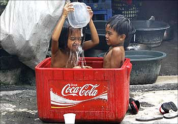 Children take a bath in a soft drink cooler on a hot day in Manila.