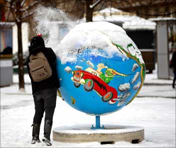 A woman cleans the snow from a globe in Copenhagen.
