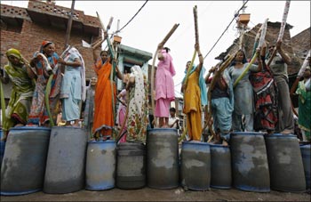 People stand atop their empty containers as they wait for a water tanker from the state-run Delhi Jal (water) Board in New Delhi.