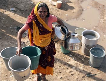 A woman carries empty water containers as she waits to collect drinking water from the municipal corporation tanker.