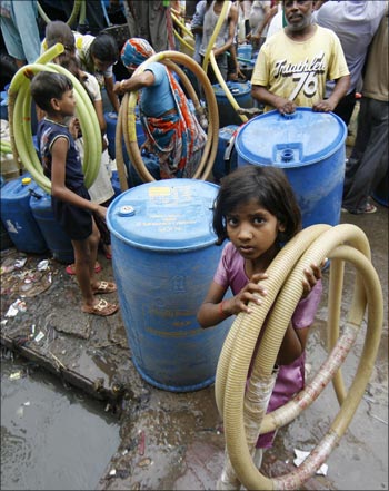 Residents of Sanjay Colony, a residential neighbourhood, carry pipes as they leave after filling their containers from a water tanker provided by the state-run Delhi Jal Board.