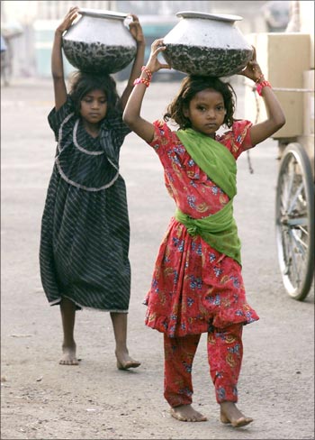Young girls carry vessels containing drinking water in New Delhi.
