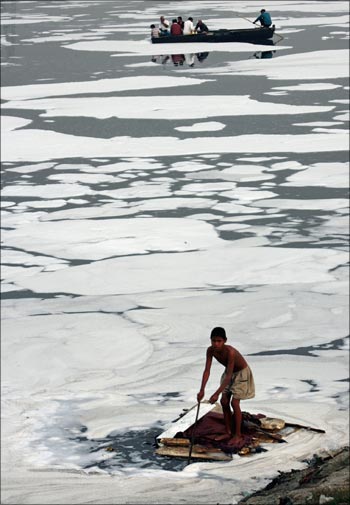 A boy looks for recyclable items in the polluted waters of the Yamuna river.