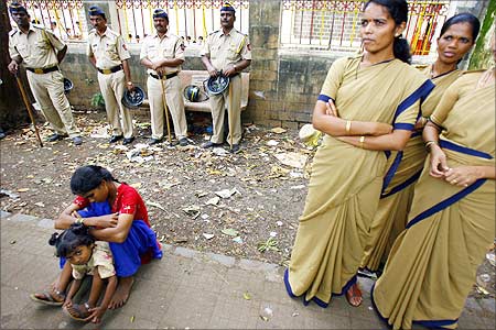 A woman and a child sit near Indian policemen during a protest against SEZ in Mumbai.