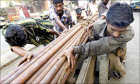Indian workers pull a cart laden with steel pipes in Mumbai.