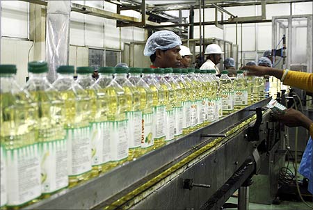 Employees fill plastic bottles with edible oil at an oil refinery plant in Mundra near Ahmedabad.