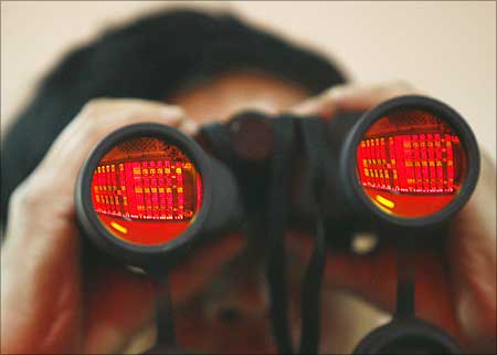 A man uses binoculars as he monitors stock movements at a stock exchange.
