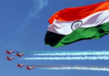 The Surya-Kiran aerobatic team of the Indian Air Force flies past the Indian flag.