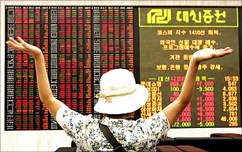 An investor stretches herself as she looks at stock price index in Seoul.
