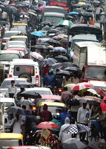 People carry umbrellas on a rainy day through a waterlogged street in Mumbai.