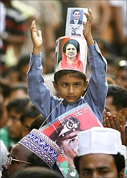 A boy with a picture of Begum Khaleda Zia around his head claps.