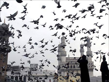Pigeons fly against the backdrop of the historic Charminar monument in Hyderabad.