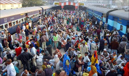Devotees wait to board a train, after taking a holy dip in the Sangam during the Magh Mela festival, at a station in Allahabad, Uttar Pradesh.