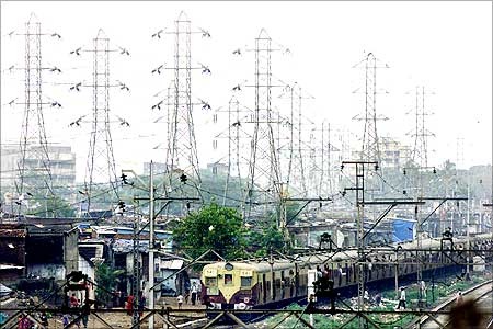 A suburban passenger train goes past a network of high voltage electric transmission towers in Mumbai.