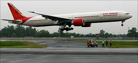 Members of the ground staff watch the inaugural flight of an Air India Boeing 777.