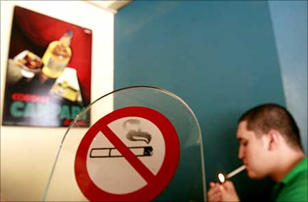 A man lights a cigarette in front of a smoking ban sign in a cafe in Chalandri suburb, north of Athens.
