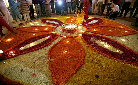 A woman lights up lamps in a flower decoration during Diwali mahurat special trading at the Bombay Stock Exchange (BSE).