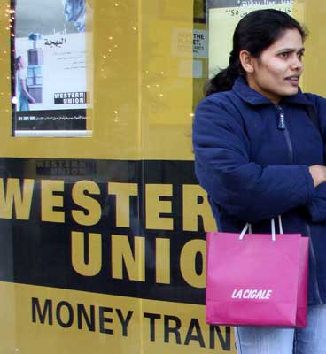 A foreign worker stands in front of Western Union, a money transfer agency in Dora, east of Beirut.
