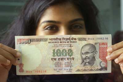 A woman displays a Rs 1,000 note.