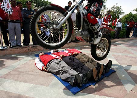 Honda's trial bike rider Motoharu Honda performs a stunt over volunteers during an event of Honda Motorcycle and Scooter India (HMSI) in New Delhi