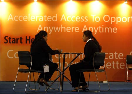 Assistants at the Microsoft stall sit in front of a billboard on the opening day of 'COM-IT 2008' an Infotech expo in Mumbai.