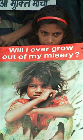 A girl child labourers holds a placard.