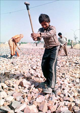 Sunny, a 6-year-old labourer who has never been to a school, and his family members break stones at a road construction site in New Delhi.