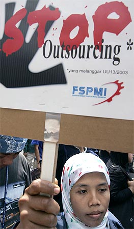 A woman holds a sign protesting against outsourcing at a rally in front of Japan's embassy in Jakarta August 14, 2008