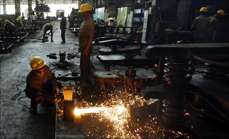 A worker uses a welding machine in a metal workshop at a railway yard in Mumbai.