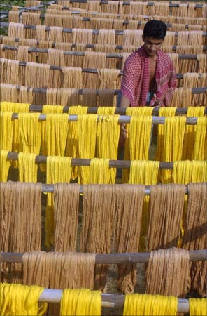 A worker hangs dyed yarn for drying at a textile mill on the outskirts of Agartala.