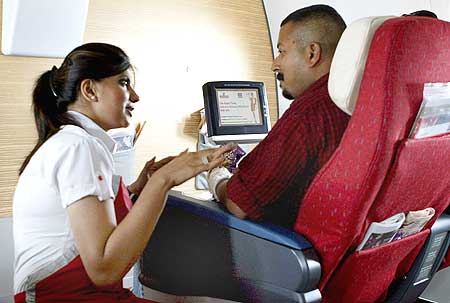 A stewardesses explains the features of the in-flight entertainment system to a Kingfisher passenger