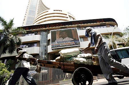 Workers pull a hand-cart in front of the Bombay Stock Exchange building in Mumbai.