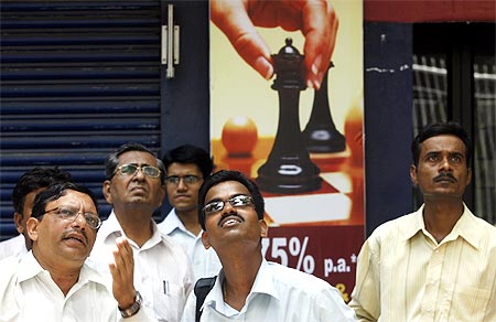 People look at a large screen displaying the Sensex on the facade of the BSE building in Mumbai.