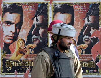 An Indian policeman stands in front of movie posters in Srinagar.