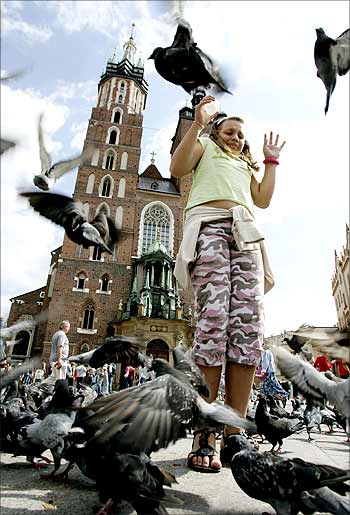 A girl reacts as she feeds pigeons near the Mariacki Church in Old Square in Krakow, Poland.