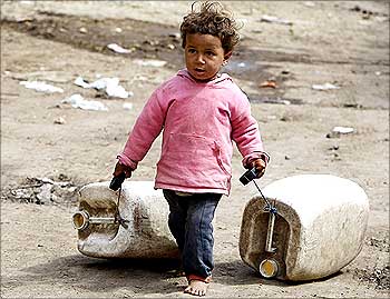 A girl drags containers to collect water at Dar El Salam, Cairo.