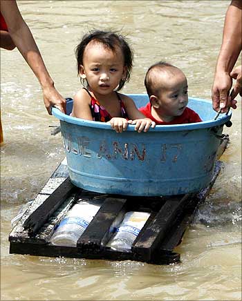 Children ride on a makeshift raft on a flooded road brought on rains by typhoon Parma in central Dagupan city in northern Philippines.