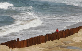A woman walks next to a wall construction site at south Coogee beach in Sydney.