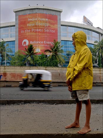 A boy looks at an auto rickshaw passing by the Reliance Energy building in Mumbai.