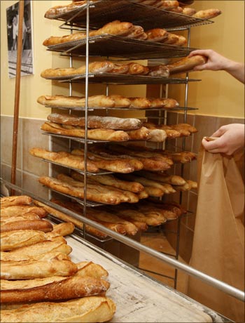 A worker displays baguettes (French stick), bread made with organic flour, at a bakery in Paris.