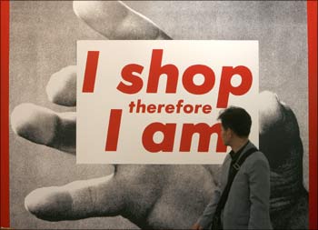 A man looks at a sign 'I shop, therefore I am', highlighting American consumerism.