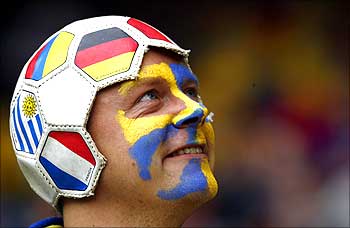 A Sweden fan wearing a hat made from a football waits before Sweden's soccer match against Spain.