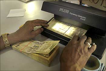 A cashier checks Indian currency notes in a bank.